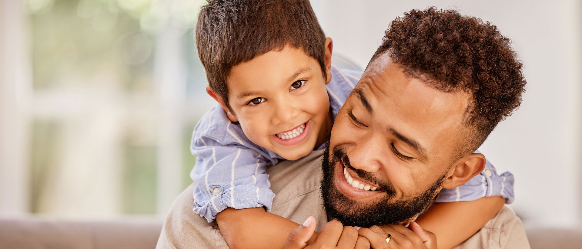 The image shows a man and a child smiling and embracing each other.