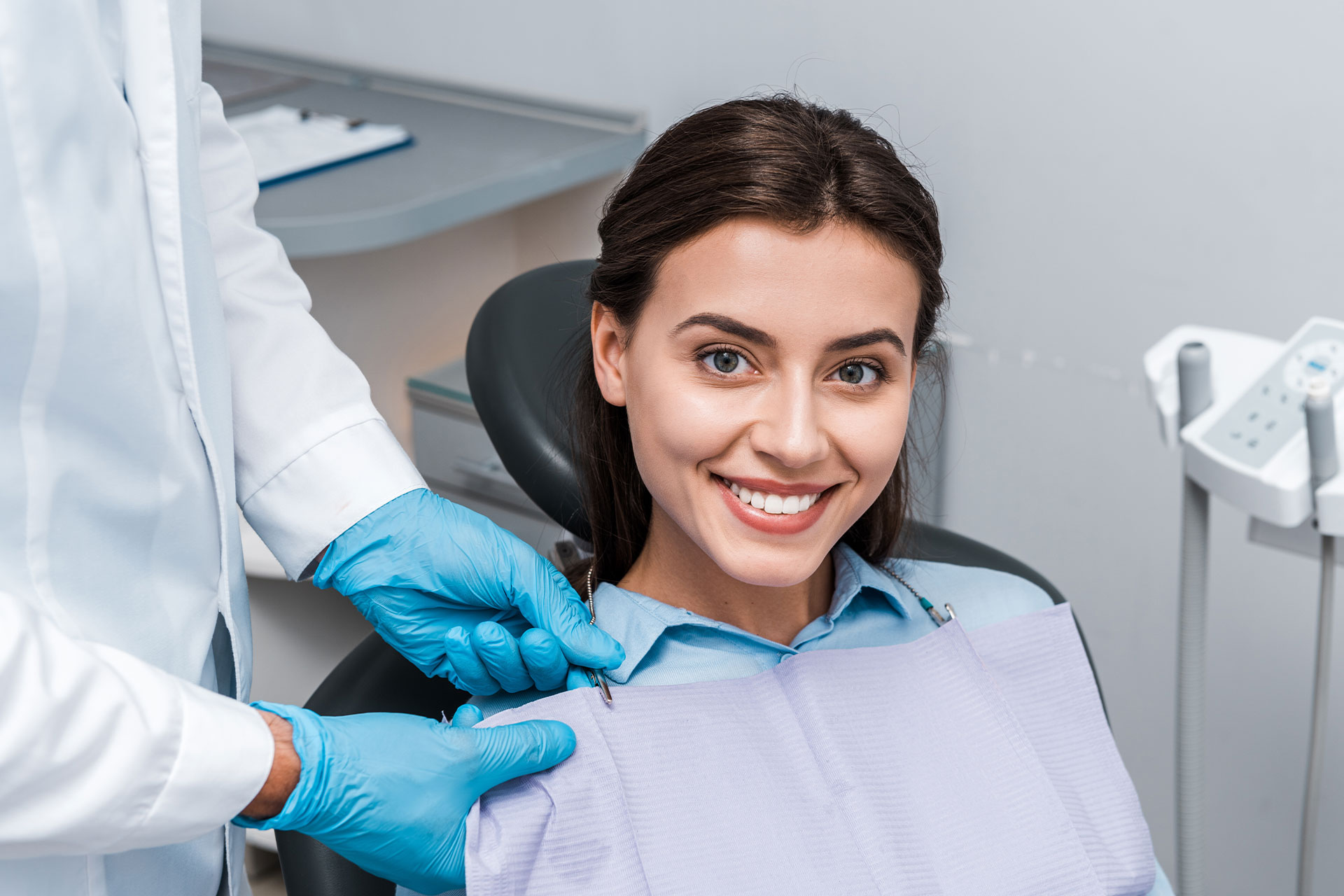 The image shows a dental hygienist in a professional setting, smiling at the camera while adjusting a patient s mouthguard.