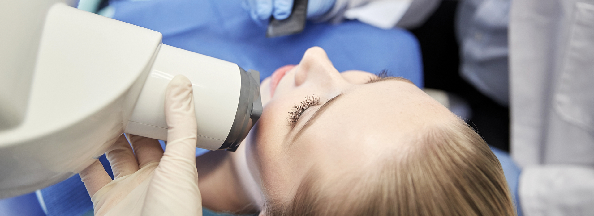 A woman undergoing a medical procedure with a device attached to her face, in the presence of medical professionals.