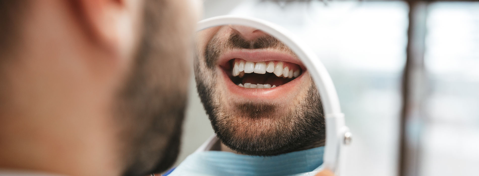 A man with a toothbrush in his mouth, smiling and looking upwards at the camera.