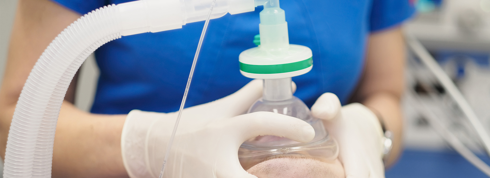 A person in a white lab coat is holding a clear plastic bag with a green cap, which appears to contain medical equipment or supplies.