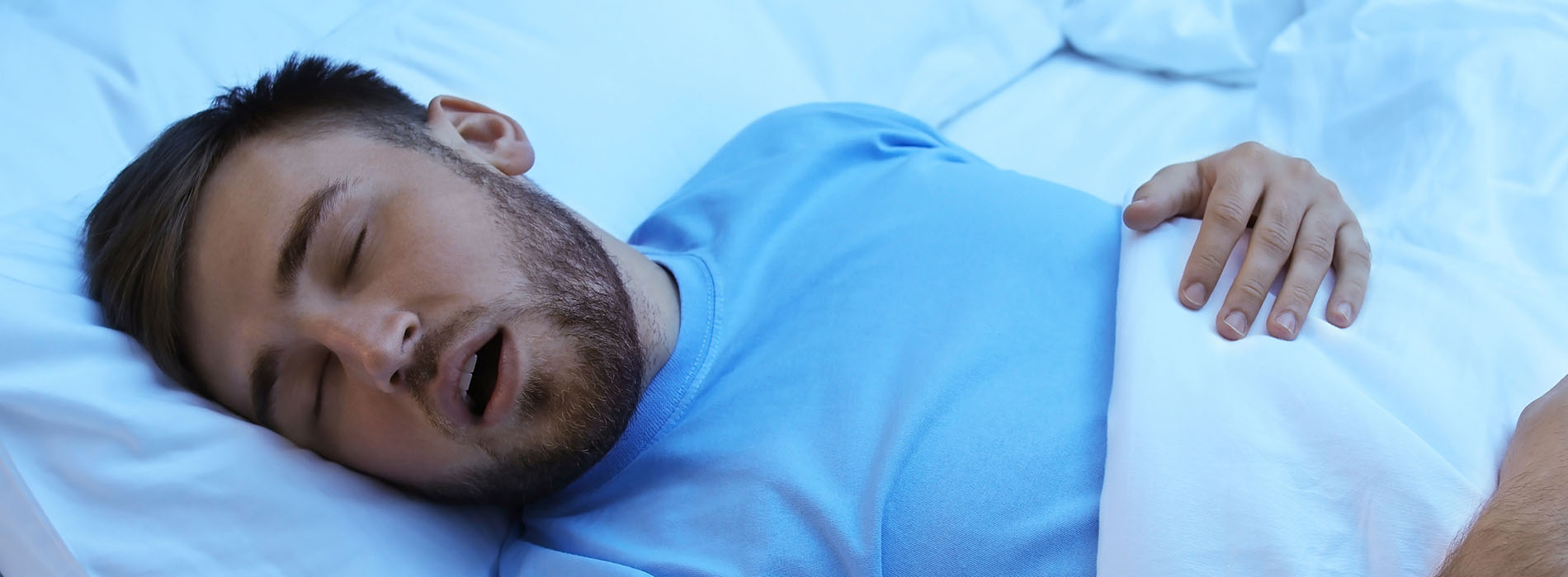 A man in a hospital bed with an open mouth, appearing to be asleep.