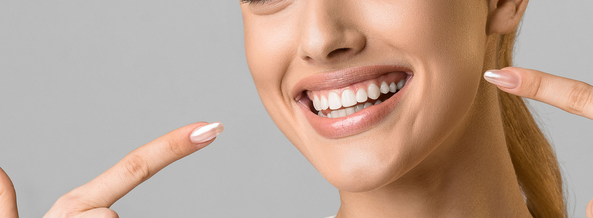 The image shows a woman with a radiant smile, holding up her index finger and thumb to indicate the number one.