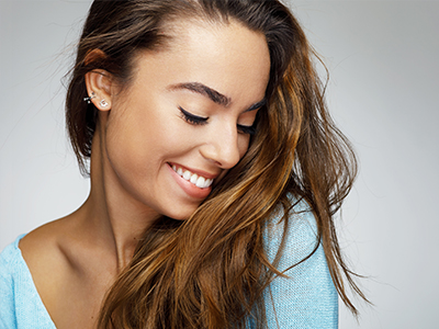 A woman with long hair and a radiant smile, looking to the side.