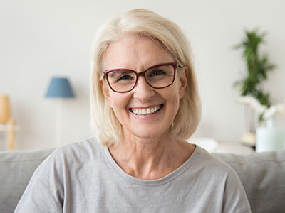 A woman with blonde hair, wearing glasses and a blue top, smiling at the camera.