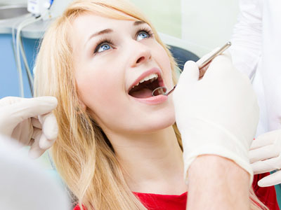 A woman receiving dental treatment with a dentist performing the procedure.