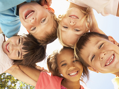 A group of children smiling and posing together outdoors.